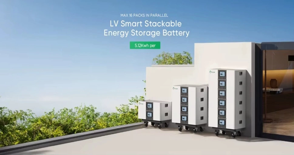 Three white stackable battery units with digital displays on a sunny patio beside greenery and a modern building.