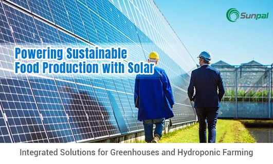 Two people walking beside solar panels and greenhouses.